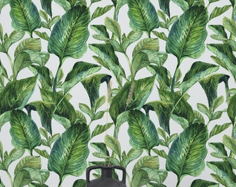 May include: A black ceramic vase with a handle sits on a wooden tray in front of a white background with a green tropical leaf pattern.