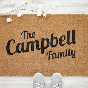 May include: A brown coir doormat with the text "The Campbell Family" in black lettering.