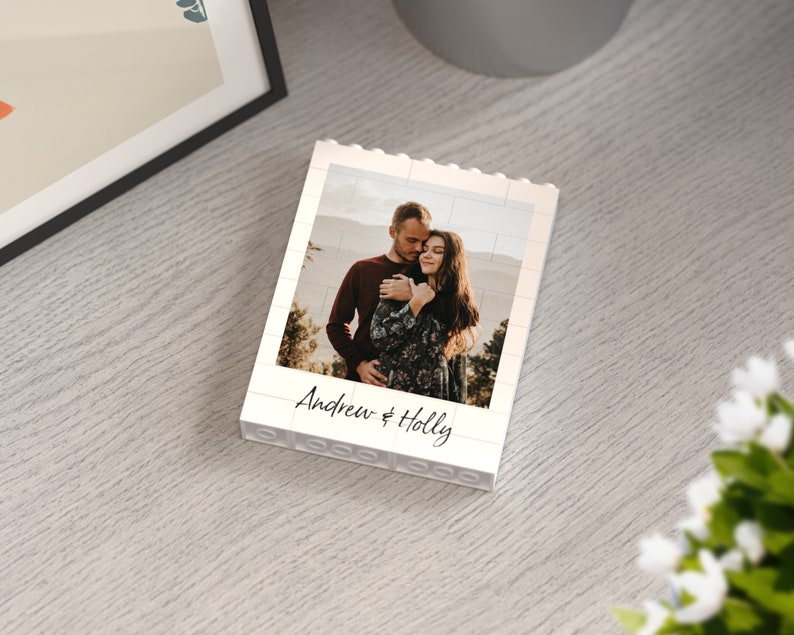 May include: White Lego-style photo frame with a photo of a couple embracing. The frame has the text "Andrew & Holly" printed on the bottom.