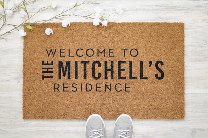 May include: A brown coir doormat with the text "Welcome to The Mitchell's Residence" in black lettering.