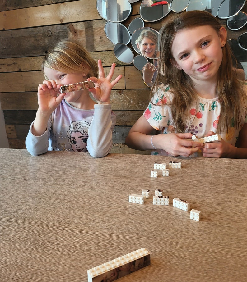Personalised Father’s Day gift featuring a custom photo printed on a Lego-style brick plaque with the text “Daddy & Me.” The unique keepsake shows a child sitting on their father’s shoulders, displayed on a wooden surface with a red heart detail and decorative items nearby.