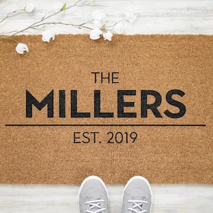 May include: A brown coir doormat with the text "THE MILLERS EST. 2019" in black lettering.