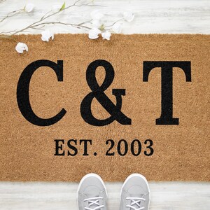 May include: A brown coir doormat with the letters C & T and the text "EST. 2003" in black.
