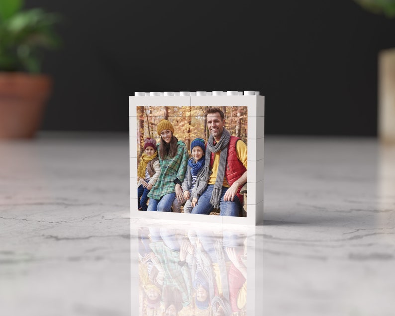 May include: A white photo block with a picture of a family of four in a forest setting. The family is wearing fall-themed clothing and smiling at the camera.