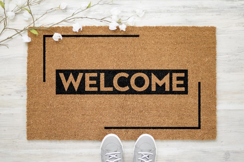 May include: A brown coir doormat with a black border and the word "WELCOME" in black lettering.