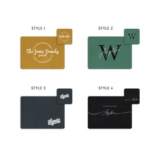 May include: Four different styles of personalised placemats. The first placemat is yellow with a circle and the text "The Jones Family Gabriella". The second placemat is green with a large white "W" and the text "Angelina". The third placemat is black with the text "Lewis" in white. The fourth placemat is black with the text "The Westwood Family Angelina" in white.