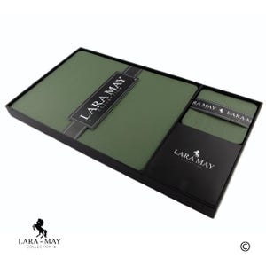 Può includere: Un set di tovagliette e sottobicchieri verdi in una scatola nera. La scatola riporta il testo "Lara May Collection".