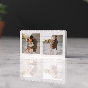 May include: A white photo frame with two images of a family of three on a beach. The family is smiling and holding each other. The frame is made of white plastic and has a simple design.
