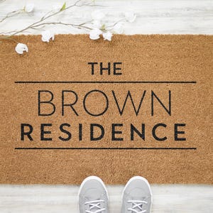 May include: A brown coir doormat with the text "THE BROWN RESIDENCE" in black lettering.