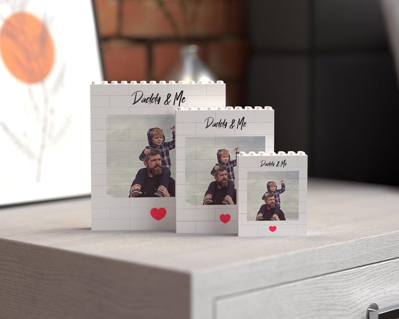 Set of three customizable photo blocks made from white building bricks, each featuring a cherished "Daddy & Me" image and elegant black script, accented by a bright red heart. Available in three different sizes, this charming collection is perfect as a meaningful Father's Day gift or personalized home decor keepsake.