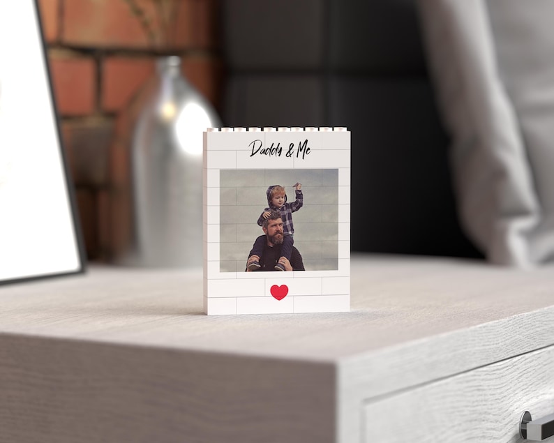 Personalized standing photo block crafted from white building bricks, showcasing a custom printed photo of a father and child moment, labeled "Daddy & Me" in stylish text, and finished with a charming red heart detail. Perfect as a unique and sentimental Father's Day gift or home decor keepsake.