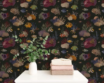 May include: Dark wallpaper with a repeating pattern of colourful coral, fish, and sea life. The design includes red, purple, yellow, and blue elements. A white table holds a vase with green leaves and a stack of folded towels.