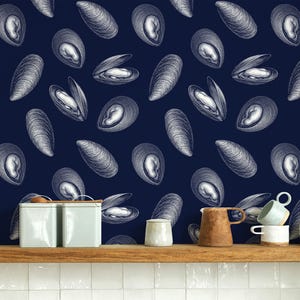Può includere: Carta da parati blu scuro con un motivo ripetuto di illustrazioni di conchiglie di cozze bianche. Le conchiglie sono raffigurate in varie posizioni, alcune aperte e altre chiuse. Stoviglie in ceramica su una mensola di legno.