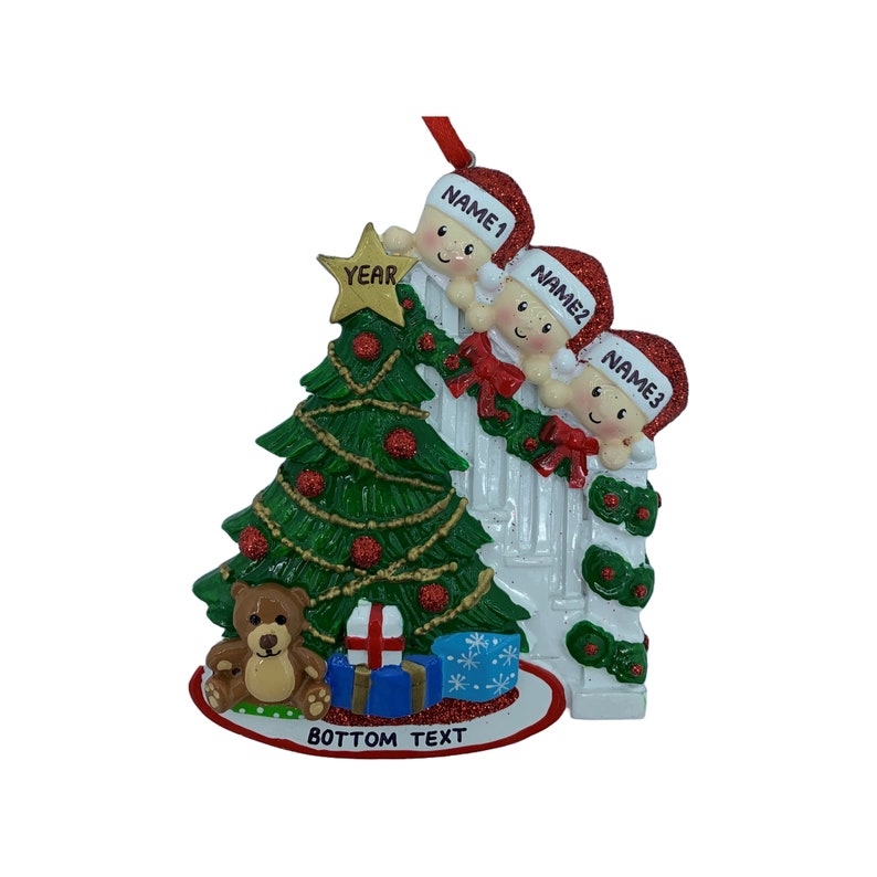 May include: A personalized Christmas ornament featuring three children peeking over a white picket fence with a green Christmas tree, a teddy bear, and presents. The ornament includes the text "YEAR", "NAME1", "NAME2", "NAME3", and "BOTTOM TEXT".
