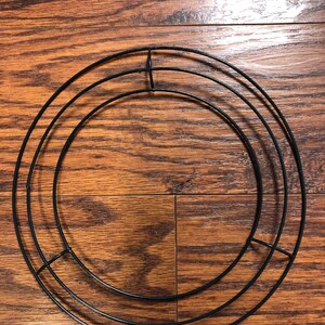 Op de afbeelding: Een zwart metalen kransframe met drie concentrische cirkels. Het frame is ontworpen voor knutselen en decoreren.