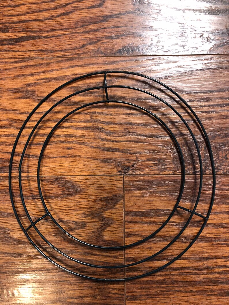 Op de afbeelding: Een zwart metalen kransframe met drie concentrische cirkels. Het frame is ontworpen voor knutselen en decoreren.