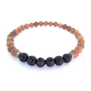 May include: A bracelet made of wooden and lava stone beads. The bracelet features light brown wooden beads and black lava stone beads. Silver-coloured metal spacers are placed between the different bead types.