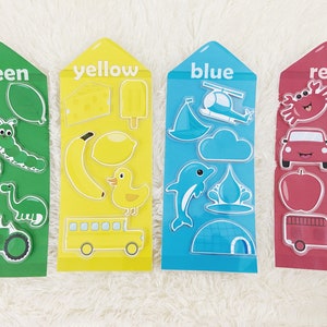 May include: Four colorful cards with different images on each. The cards are labeled "green", "yellow", "blue", and "red". Each card has a variety of images related to the color, such as a green caterpillar, a yellow banana, a blue dolphin, and a red apple.