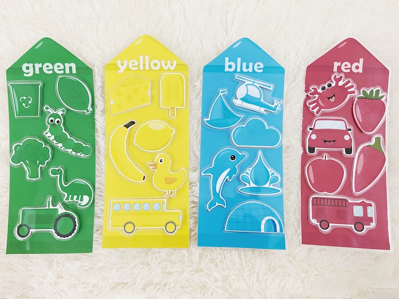 May include: Four colorful cards with different images on each. The cards are labeled "green", "yellow", "blue", and "red". Each card has a variety of images related to the color, such as a green caterpillar, a yellow banana, a blue dolphin, and a red apple.