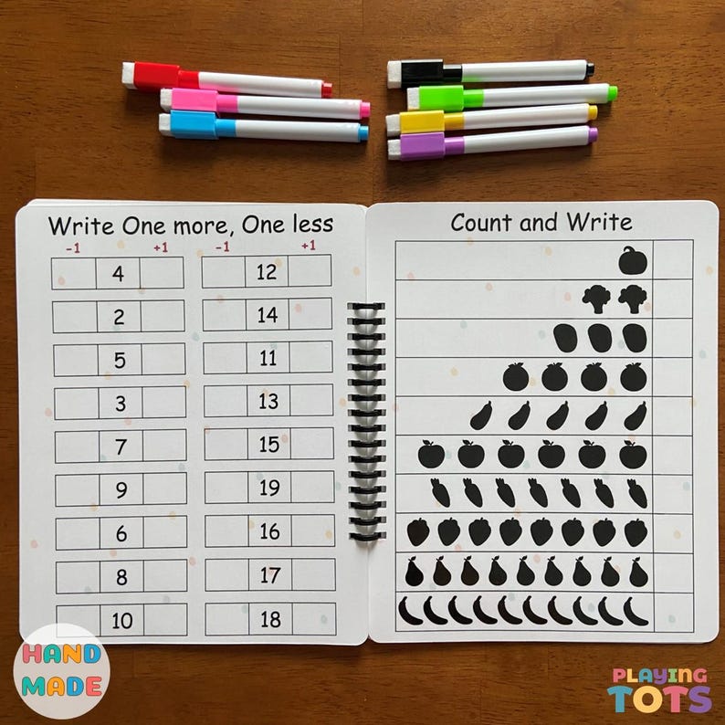 May include: A spiral-bound educational workbook with number exercises and fruit and vegetable counting activities. Includes colorful markers in red, pink, blue, green, yellow, and purple. The workbook has the text "Write One more, One less" and "Count and Write".