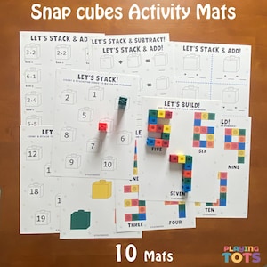 May include: Educational activity mats for snap cubes. The mats feature math problems and number building activities. The mats are white with colorful cube illustrations and the text "Snap cubes Activity Mats". The set includes 10 mats.