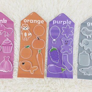 May include: Four colorful cards with the words "pink", "orange", "purple", and "gray" printed on them. Each card has various images of objects in the corresponding color.