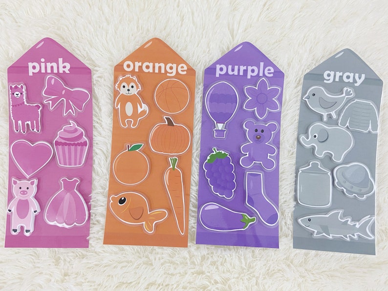 May include: Four colorful cards with the words "pink", "orange", "purple", and "gray" printed on them. Each card has various images of objects in the corresponding color.