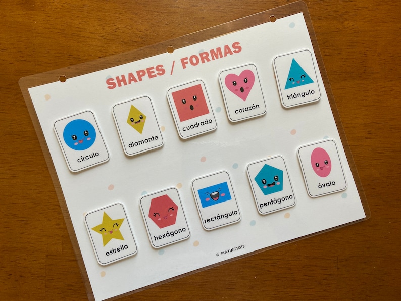 May include: A colorful educational chart with images of different shapes, including a circle, diamond, square, heart, triangle, star, hexagon, rectangle, pentagon, and oval. Each shape has a cute cartoon face and the Spanish word for the shape is written below it. The chart is titled "Shapes/Formas".