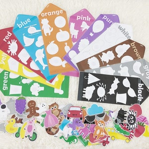 May include: A set of colorful learning cards with matching picture pieces. The cards feature different colors, including red, orange, yellow, green, blue, purple, white, brown, gray, and black. Each card has a silhouette of an object, and the matching picture pieces can be placed on top of the silhouette.