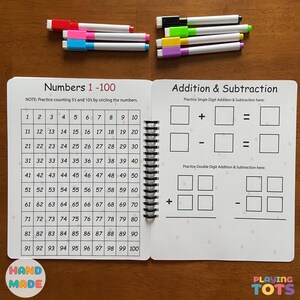 May include: A spiral-bound educational activity book for children, featuring number practice from 1 to 100 and addition/subtraction exercises. Includes colorful markers in various colors. The book is labeled "Hand Made" and "Playing Tots".