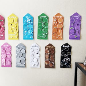 May include: A set of 12 color cards with various images on each card. The cards are labeled with the color name: red, yellow, blue, green, orange, purple, pink, gray, white, brown, black. Each card has a different color background and features various images related to that color.