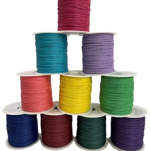 May include: Ten spools of waxed cotton cord in various colors, including teal, purple, yellow, green, red, burgundy, navy, and pink. The spools are stacked in a pyramid shape.