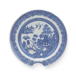 Puede incluir: Un plato de cerámica azul y blanco con un diseño clásico de Willow. El plato presenta una escena de paisaje detallada con un puente, una pagoda y pájaros. El plato tiene una muesca única en el lateral, ideal para servir alimentos.
