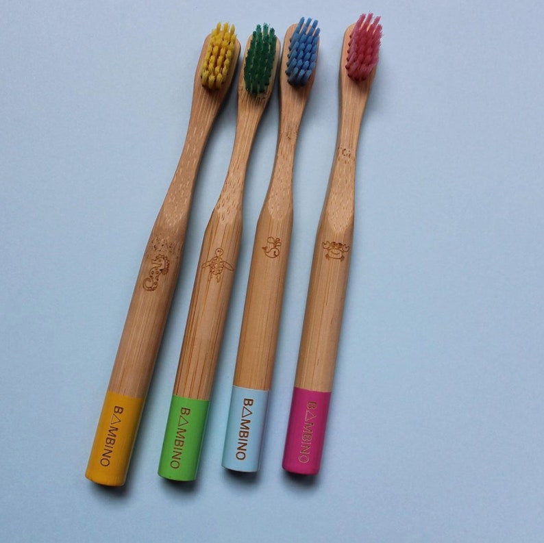 May include: Four bamboo toothbrushes with colorful bristles and the word "BAMIBINO" printed on the handles. The toothbrushes are yellow, green, blue, and pink.