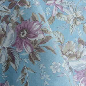 May include: A blue fabric with a floral pattern. The flowers are in shades of pink, brown, and white. The fabric has a textured surface.