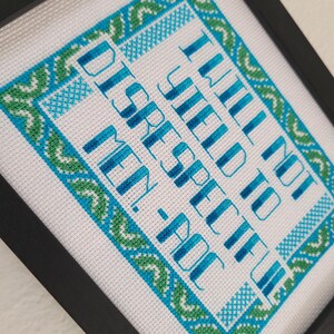 Puede incluir: Arte de punto de cruz enmarcado. La tela blanca presenta un dise&ntilde;o de borde turquesa y verde y texto turquesa que dice: "I WILL NOT BE DISRESPECTFUL TO MEN-POC."