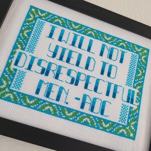 Puede incluir: Obra de arte de punto de cruz enmarcada. El texto dice "I WILL NOT YIELD TO DISRESPECTFUL MEN. - AOC" en letras azules y turquesas, rodeado por un borde verde y turquesa sobre un fondo blanco.