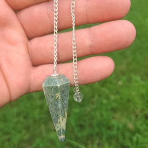 May include: A green and white speckled crystal pendulum with a silver chain.