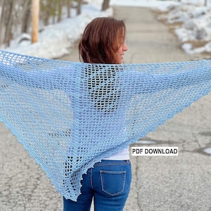 May include: A light blue crochet shawl with a delicate openwork pattern. The shawl is draped over the shoulders of a person standing outdoors. The text "PDF DOWNLOAD" is visible in the lower right corner of the image.