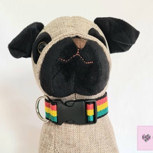May include: A black and green striped dog collar with a red and yellow stripe. The collar has a black plastic buckle and a silver D-ring.