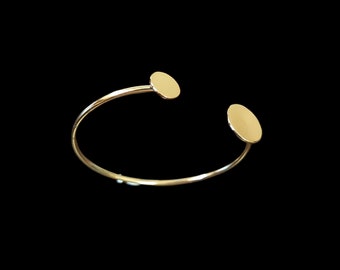May include: A gold bangle bracelet with two round, flat, gold discs on the ends.