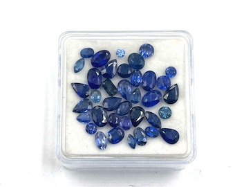 May include: A small plastic box filled with loose blue sapphire gemstones of various shapes and sizes.