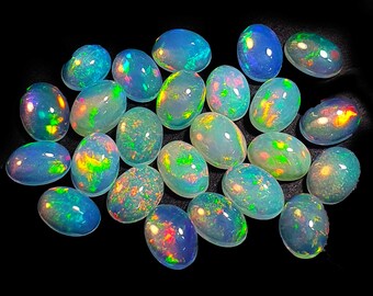 Puede incluir: Una colección de ópalos ovalados, cada uno mostrando un juego de color con destellos iridiscentes de azul, verde, amarillo y rojo. Los ópalos están sobre un fondo negro, resaltando sus vibrantes tonos y patrones únicos. Estas piedras preciosas son ideales para joyería.