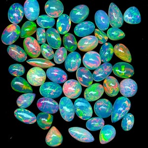Può includere: Una collezione di pietre preziose di opale di forma ovale in varie tonalità di verde, blu e rosa. Gli opali sono iridescenti e hanno una lucentezza madreperlacea.
