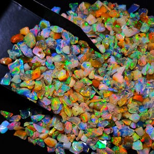 Puede incluir: Un montón grande de piedras preciosas de ópalo de colores. Los ópalos son de varias formas y tamaños y tienen un brillo iridiscente arcoíris.