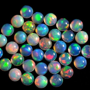 May include: A collection of round, iridescent opal cabochons in various shades of blue, green, and pink. The opals are smooth and polished, with a high luster.
