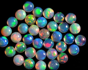 May include: A collection of round, iridescent opal cabochons in various shades of blue, green, and pink. The opals are smooth and polished, with a high luster.