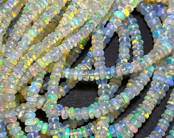 May include: Close-up of multiple strands of iridescent opal beads. The beads are small, disc-shaped, and have a translucent, milky white base color with flashes of rainbow colors. The beads are strung together, creating a textured, layered effect.