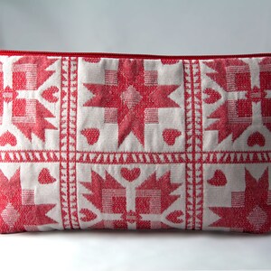 May include: A red and white zippered pouch with a geometric pattern. The pattern features stars, hearts, and squares.