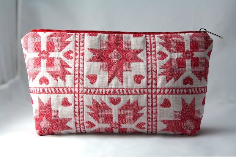 May include: A red and white zippered pouch with a geometric pattern. The pattern features stars, hearts, and squares.
